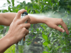 A person spraying dangerous bug spray onto themselves.